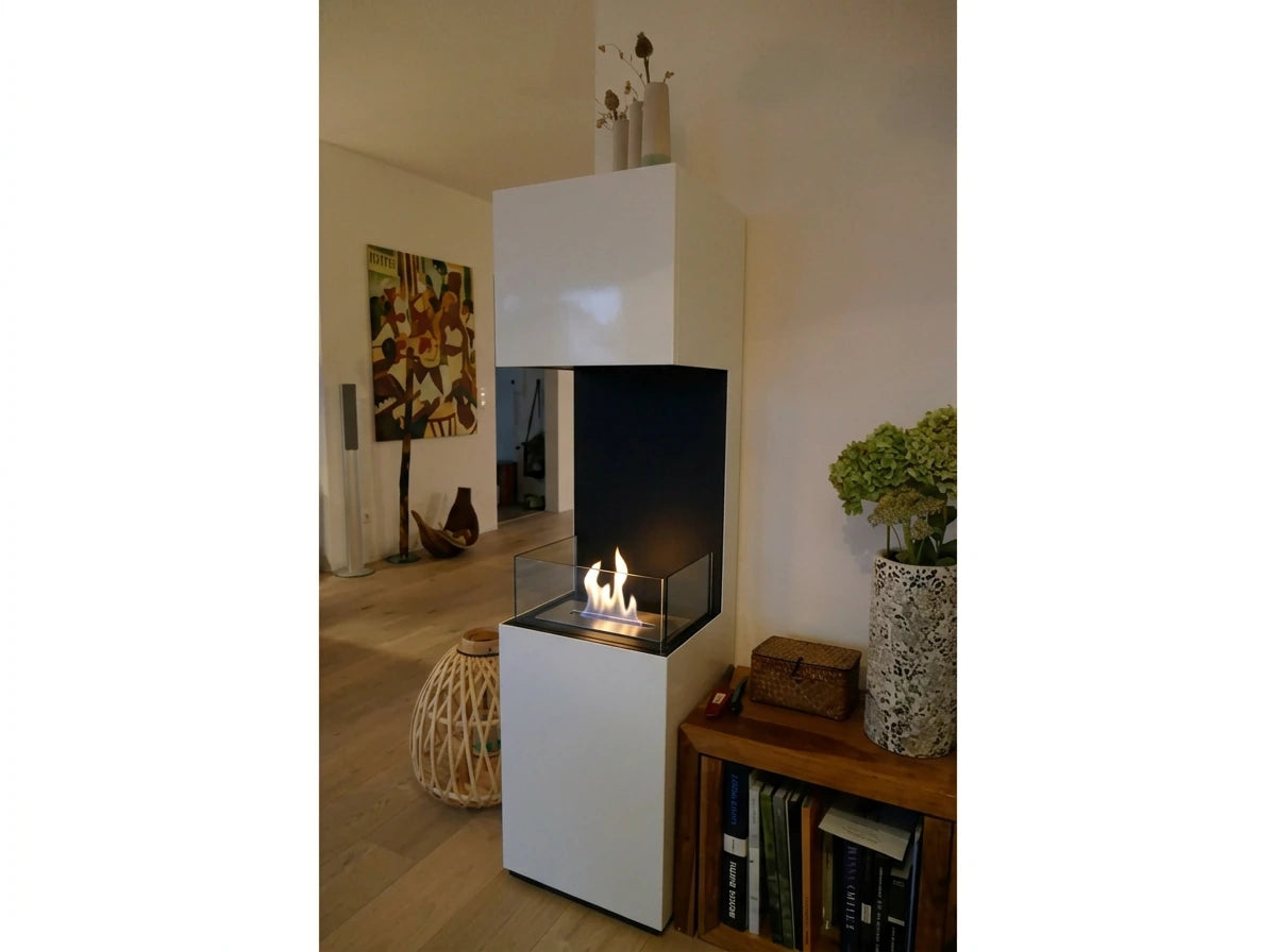 Open 3-sided white bioethanol fireplace lit as a room divider, with colorful wall art and a wooden bookshelf