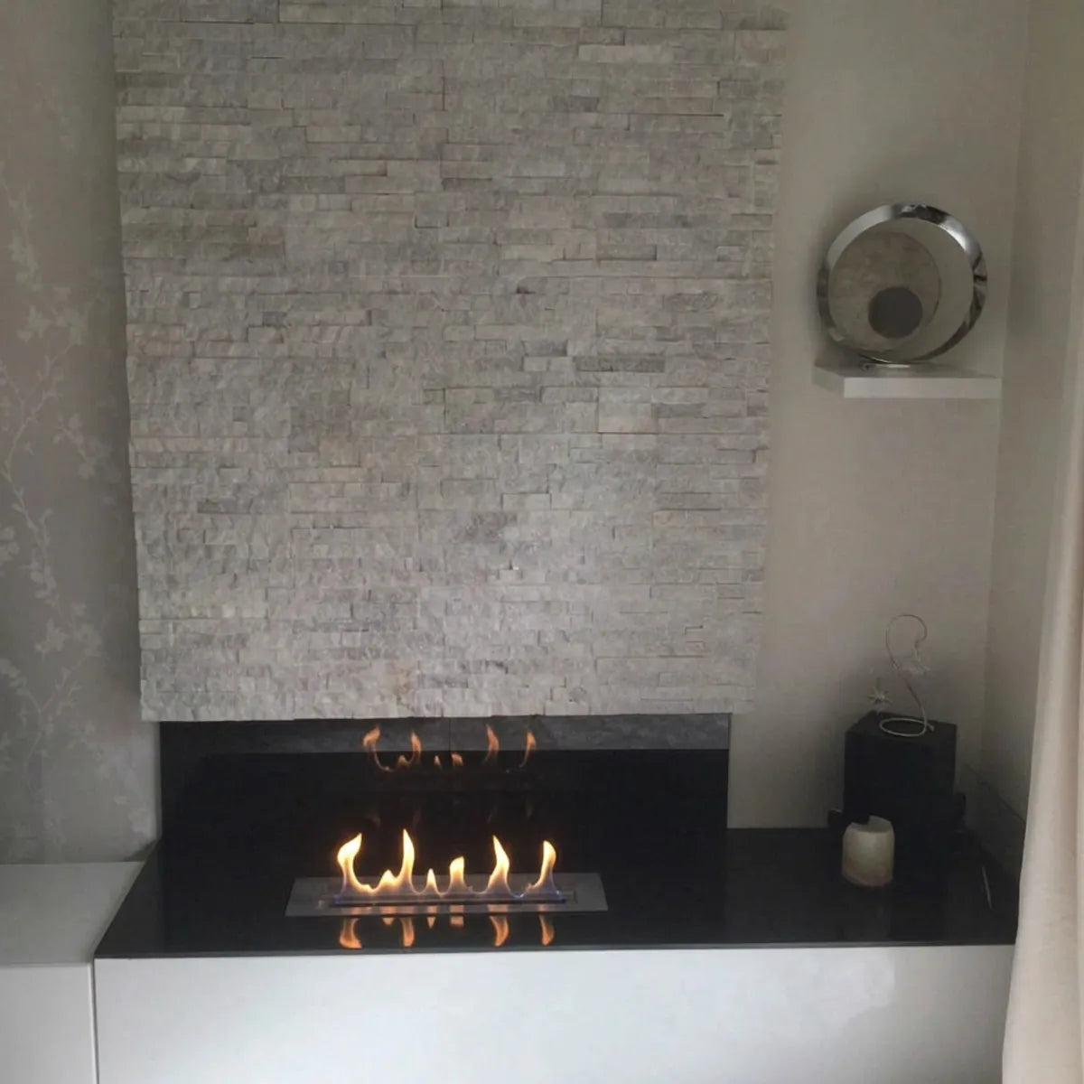 Superior 3,5L ethanol burner 60 cm built into a black frame under a stone wall, lit with realistic flames